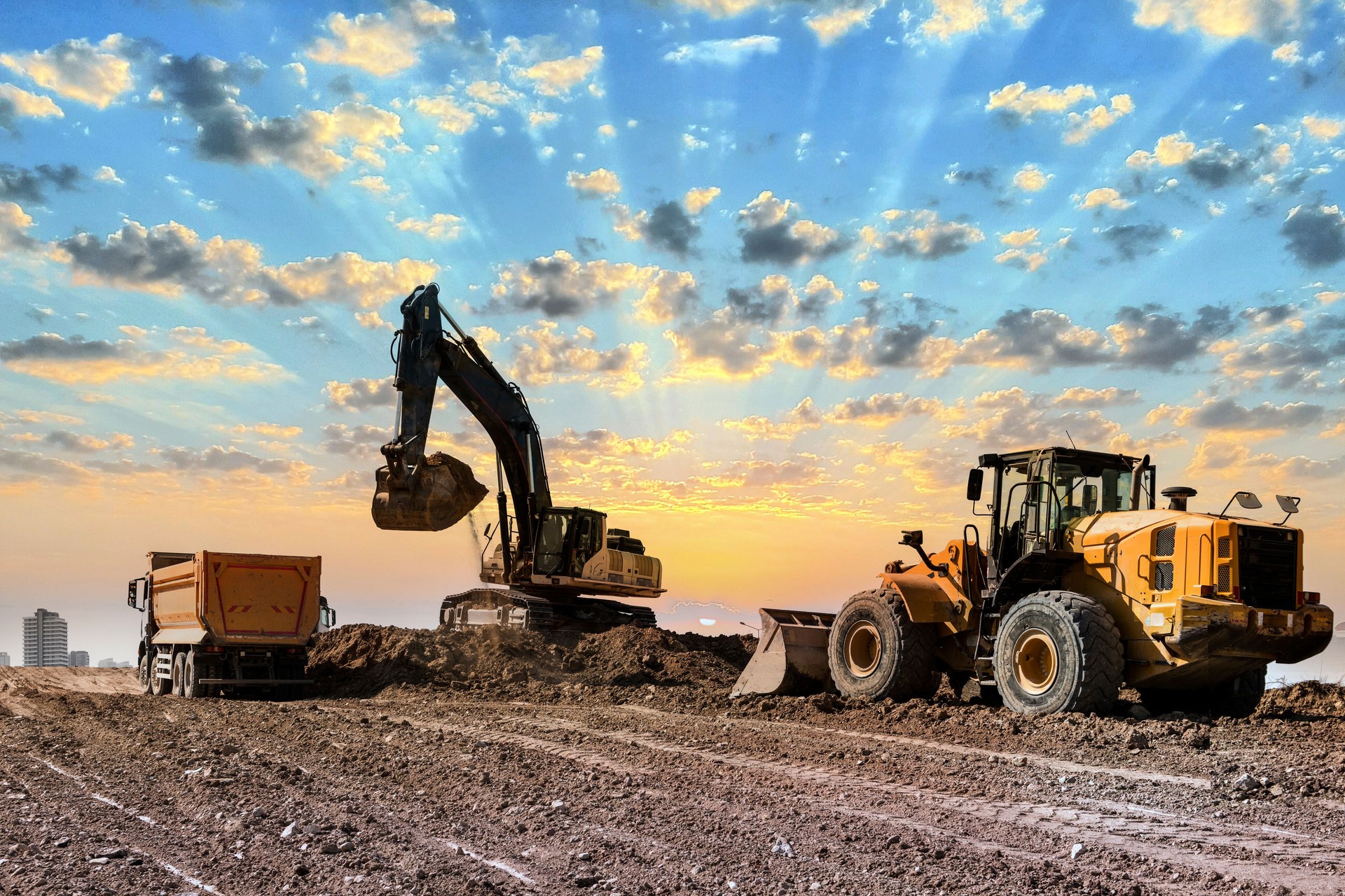 Excavators working on construction site at sunset